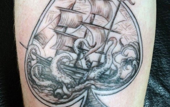 手臂黑桃轮廓图案里面有帆船和章鱼纹身图案
